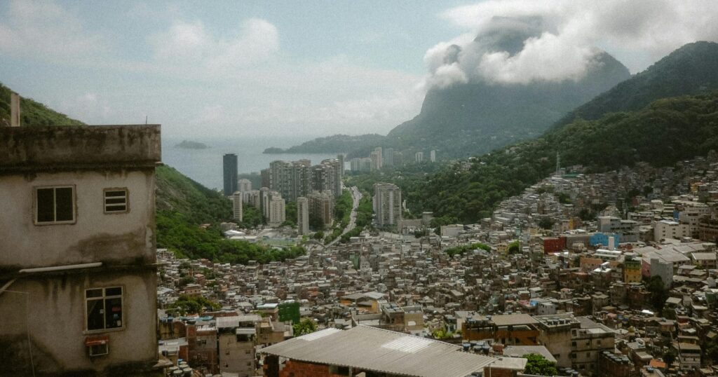 Aerial view of Rio de Janeiro cityscape with mountains and clouds in the background.